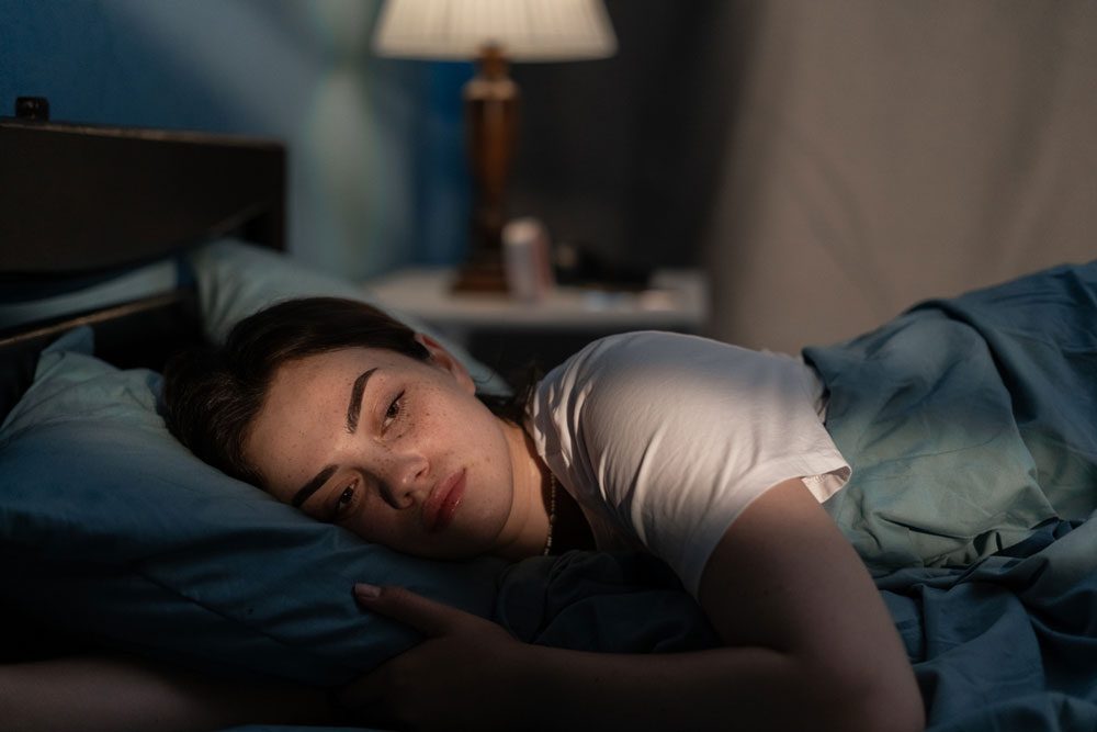 woman laying in bed at night awake, worrying.